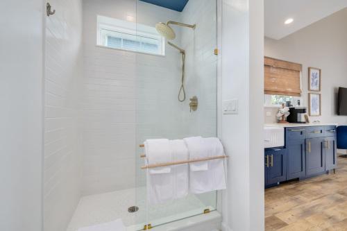 a bathroom with a shower with white towels at SANDY - Cheerful 1 bedroom tiny house with pool in Dunedin