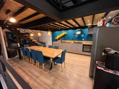 une cuisine et une salle à manger avec une table en bois et des chaises bleues dans l'établissement Loft industriel avec jacuzzi, à Le Bourgeat