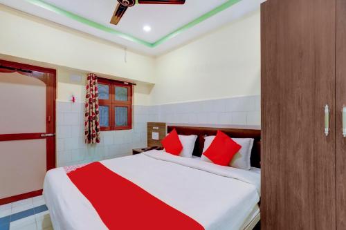 ein Schlafzimmer mit einem großen Bett mit roten Kissen in der Unterkunft OYO Sam Guest House in Chennai