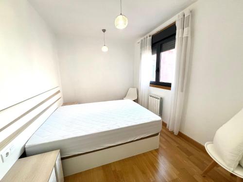 ein kleines Schlafzimmer mit einem weißen Bett und einem Fenster in der Unterkunft Apartamento Carril in Vilagarcia de Arousa