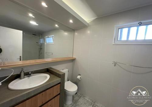 een badkamer met een wastafel, een toilet en een spiegel bij Azores Element in Livramento