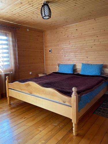 a bedroom with a large bed in a log cabin at Azaliya in Lazeshchyna