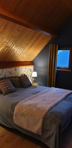 a bedroom with a large bed with a window at LE CHALET in Saint-Pierre-dʼArthéglise