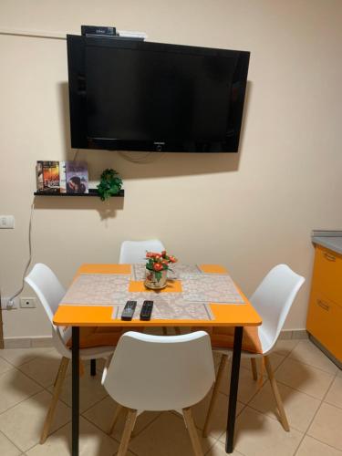 a dining room table with white chairs and a flat screen tv at Melody Apartament 1 in Golem