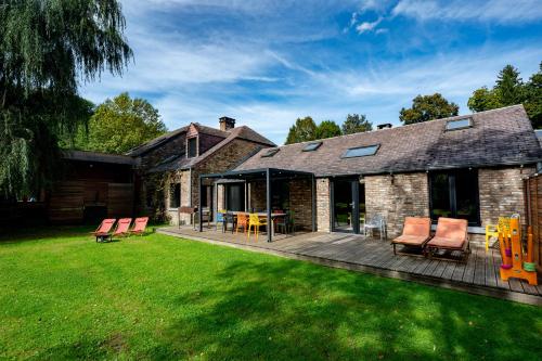 a brick house with a deck with chairs and tables at L'arche De Noé in Dinant