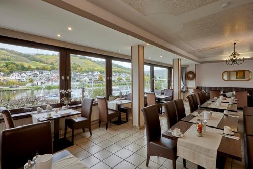 ツェル・アン・デル・モーゼルにあるMayer's Weinhotelのテーブルと椅子、大きな窓のあるレストラン