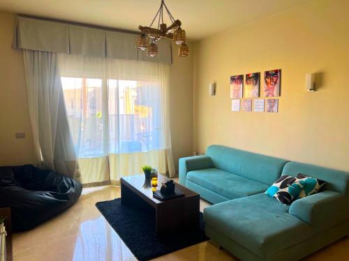 a living room with a blue couch and a table at Azzura appartment sahl hashesh with private garden in Hurghada