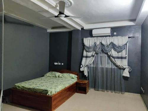 1 dormitorio con 1 cama y ventilador de techo en Belle Villa en Lomé
