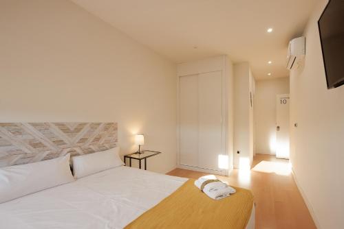 - une chambre avec un lit blanc et une tête de lit en bois dans l'établissement Habitación Villanubla, à Villanubla