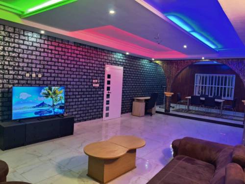 een woonkamer met een tv en een bakstenen muur bij Belle Villa in Lomé