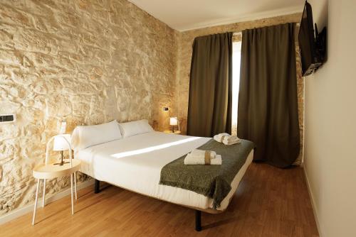 1 dormitorio con 1 cama grande y pared de piedra en Habitación Villanubla, en Villanubla