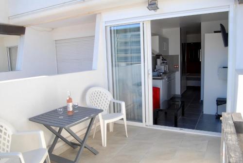 a dining table and chairs in a room with a sliding glass door at Studios Port Nature village Naturiste in Cap d'Agde