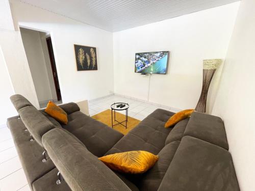 un grande divano marrone in soggiorno di La Villa Ixora, magnifique Villa avec Piscine a Les Abymes