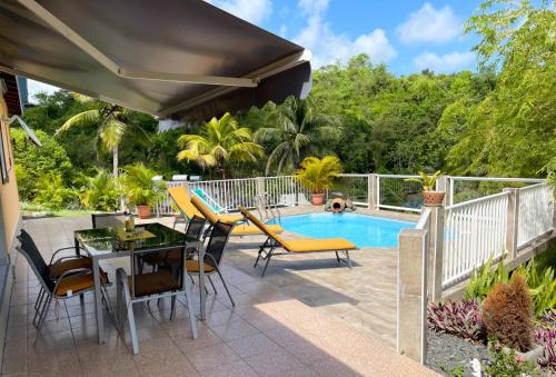 une terrasse avec une table, des chaises et une piscine dans l'établissement La Villa Ixora, magnifique Villa avec Piscine, à Les Abymes