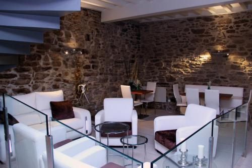 a room with white chairs and a stone wall at Hotel Montenegro Compostela in Santiago de Compostela