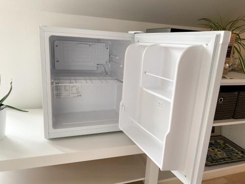 a white refrigerator with its door open on a shelf at Husrum på Österlen in Tomelilla