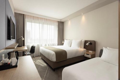 a hotel room with two beds and a television at Holiday Inn - Eindhoven Airport by IHG in Eindhoven
