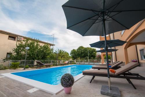 a swimming pool with an umbrella and two chairs and a table at Villa Ljubica 2 in Vodice