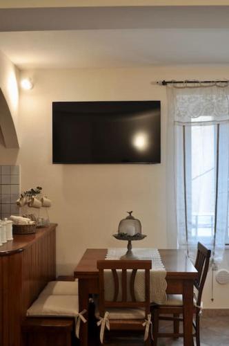 a dining room with a table and a television on the wall at Appartamento Nara in Pietrasanta