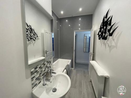 a white bathroom with a sink and a toilet at OCEAN ESCAPE 200m From the Sea, High Spec Town Centre Entire Flat, 3 Bedrooms, TVs All Rooms in Porthcawl