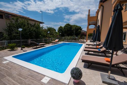 a pool with chairs and umbrellas next to a house at Villa Ljubica 2 in Vodice