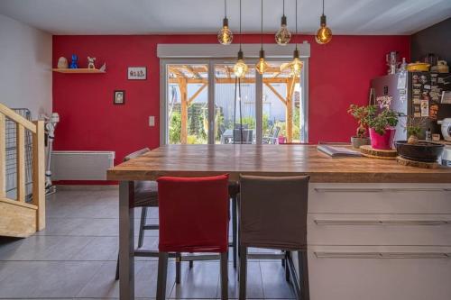 - une cuisine avec des murs rouges et un comptoir en bois avec des chaises dans l'établissement Charmante maison de Lotissement, 6 couchages, à Portes-lès-Valence