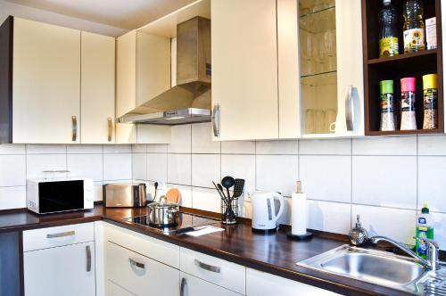a kitchen with white cabinets and a sink at Deluxe! Hbf-Nähe mit Kingsize-Bett, 65 m2 in Duisburg