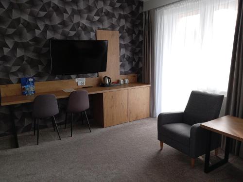 a living room with a desk with a television and chairs at Karczma u Jana in Kuczów
