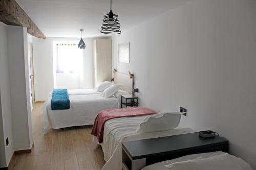 a white room with two beds and a window at Bosque de los sauces in Béjar