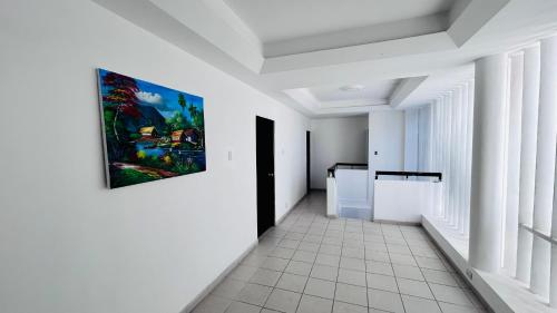 um corredor com paredes brancas e uma pintura na parede em Sulam Hotel Nicaragua em Managua