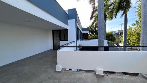 Dieses weiße Haus verfügt über einen Balkon mit Palmen. in der Unterkunft Sulam Hotel Nicaragua in Managua