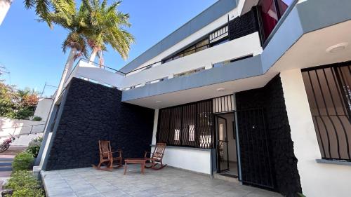 ein Gebäude mit zwei Stühlen und einer Palme in der Unterkunft Sulam Hotel Nicaragua in Managua