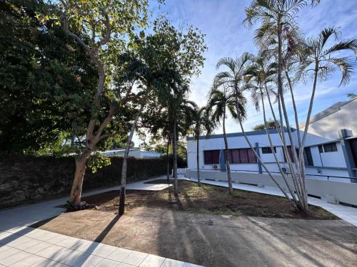 een wit gebouw met palmbomen ervoor bij Sulam Hotel Nicaragua in Managua