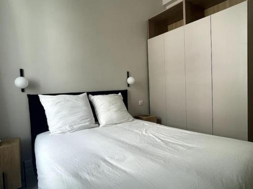 une chambre avec un lit blanc avec deux oreillers dans l'établissement Appartement Centre Cannes, à Cannes