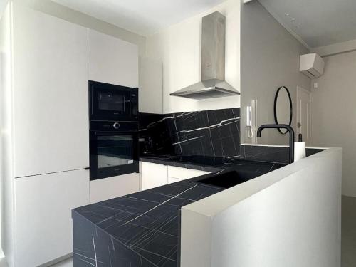 une cuisine avec des armoires blanches et un comptoir noir dans l'établissement Appartement Centre Cannes, à Cannes