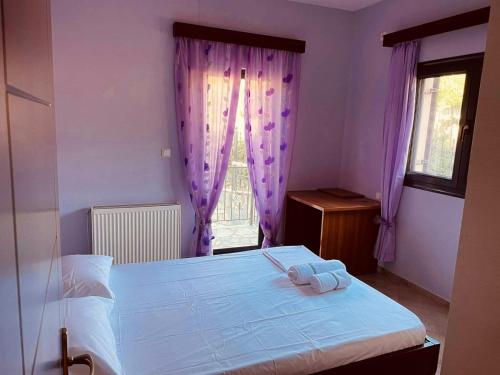 a bedroom with a bed and a window with purple curtains at Villa Athamanio - Premium in Athamanio