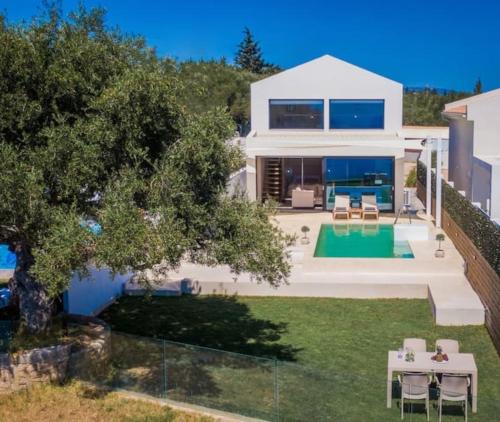 a large white house with a backyard with a swimming pool at Olive Zen Villa Zante in Zakynthos Town