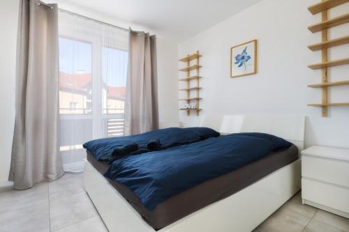 a bedroom with a bed with blue sheets and a window at Dwupiętrowy Apartament Beskid View in Bielsko-Biała