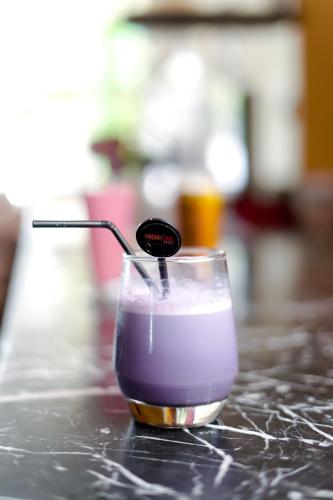 a glass of purple liquid sitting on a counter at Front One Hotel Purwodadi in Purwodadi