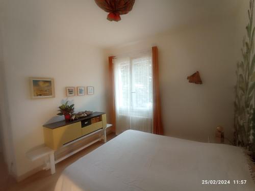 een slaapkamer met een bed, een dressoir en een raam bij Auprès de mon arbre in Thuir