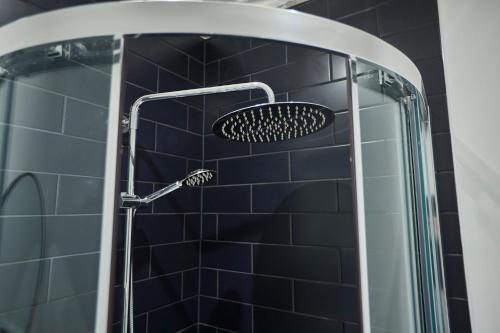 a shower with a shower head in a bathroom with black tiles at Ocean View in Hornsea