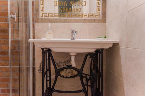 a bathroom with a white sink and a black chair at Apartment in Antique Museum Filip in Krklino