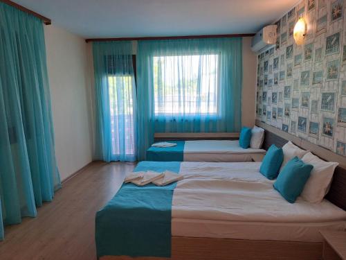 2 camas en una habitación con cortinas azules en Къща за гости КАТИ, en Kiten