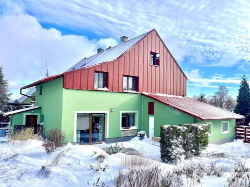 MěděnecにあるHorský dům Kilianの雪中の赤と緑の家