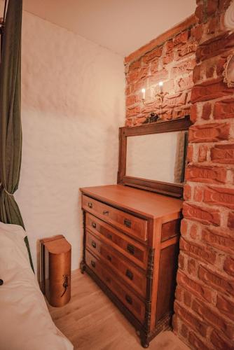 a bedroom with a wooden dresser and a brick wall at Apartment in Antique Museum Filip in Bitola