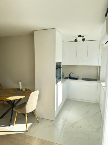 a kitchen with white cabinets and a wooden table at Central Boulevard Apartment 2 in Šiauliai