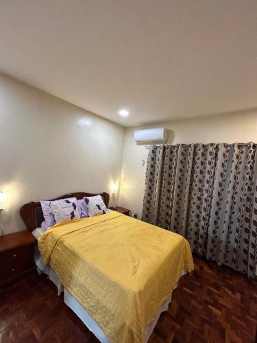 1 dormitorio con 1 cama con colcha amarilla en Loidas place, en Talisay