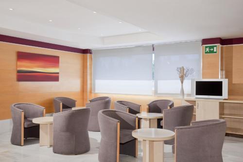 poczekalnia z krzesłami i stołami oraz telewizorem w obiekcie Holiday Inn Express Alcobendas by IHG w mieście Alcobendas