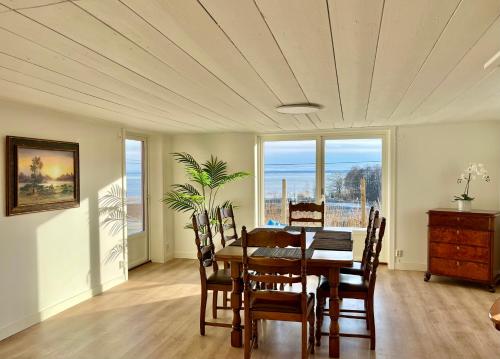 a dining room with a table and chairs and windows at Flemma Gård The lake view with sauna in Vreta Kloster