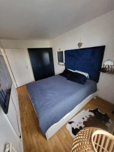 une chambre avec un grand lit avec une tête de lit bleue dans l'établissement appartement lumineux à 10mn de Paris, à Romainville